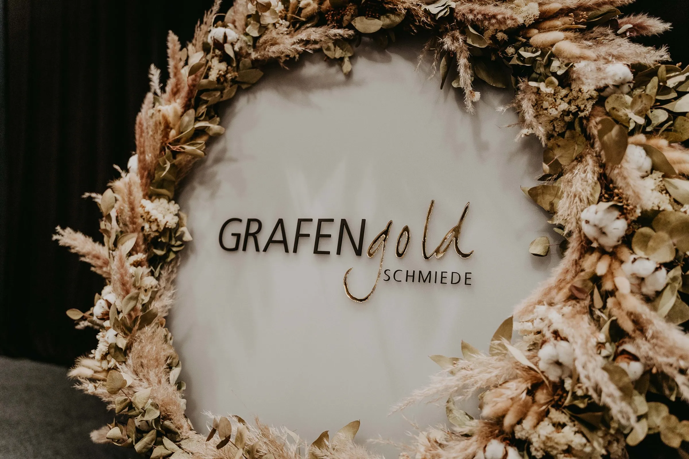 Grafengold-Logo in einem Kranz aus Trockenblumen