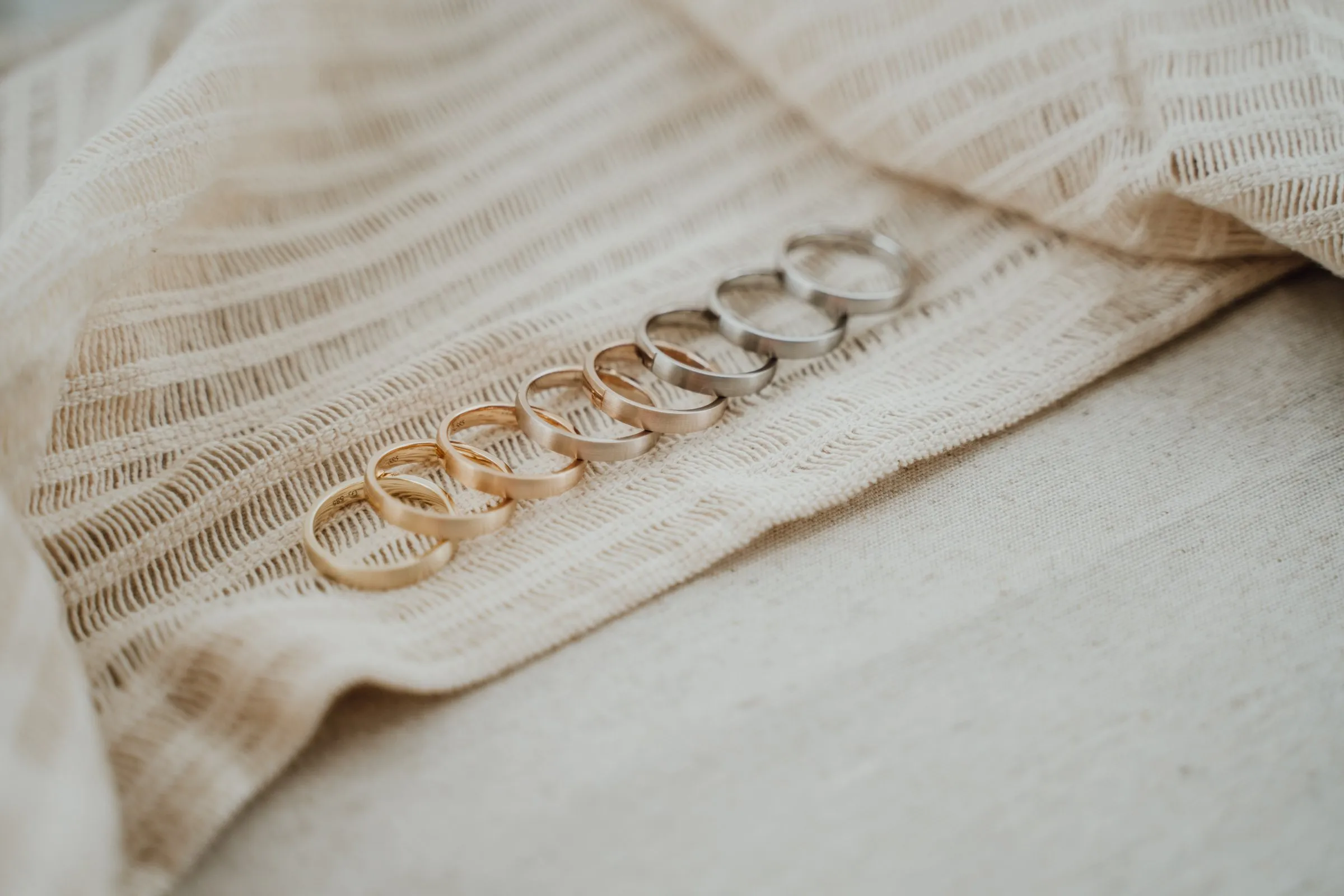 Trauring-Musterringe in Gold und Weißgold, aufgereiht auf Stoff