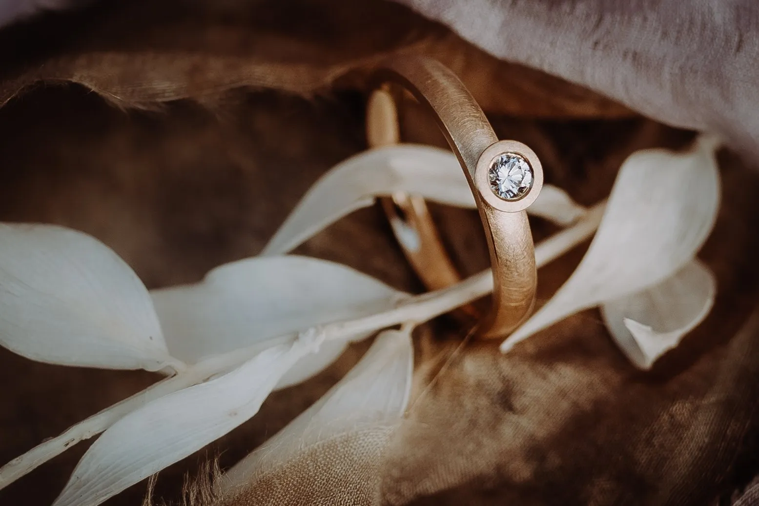 Handgefertigter Verlobungsring aus Gelbgold mit Brillant auf hellen Blättern